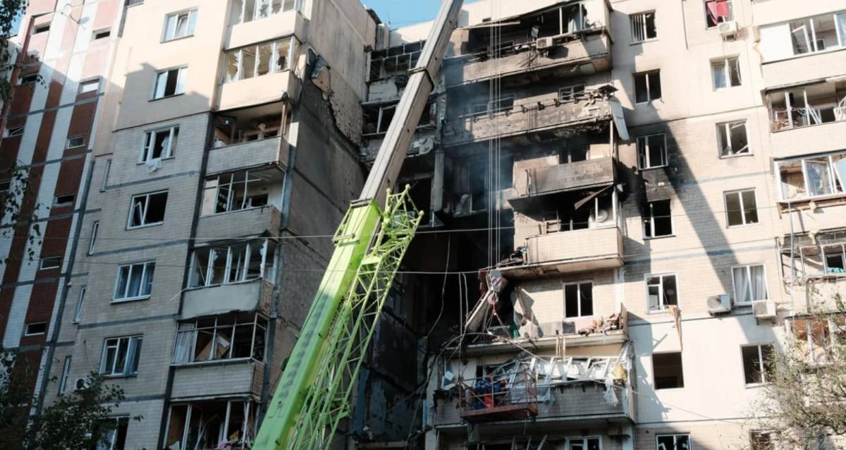 Зруйнований будинок у Києві, постраждалий від обстрілів, на тлі якого надається допомога киянам від обстрілів